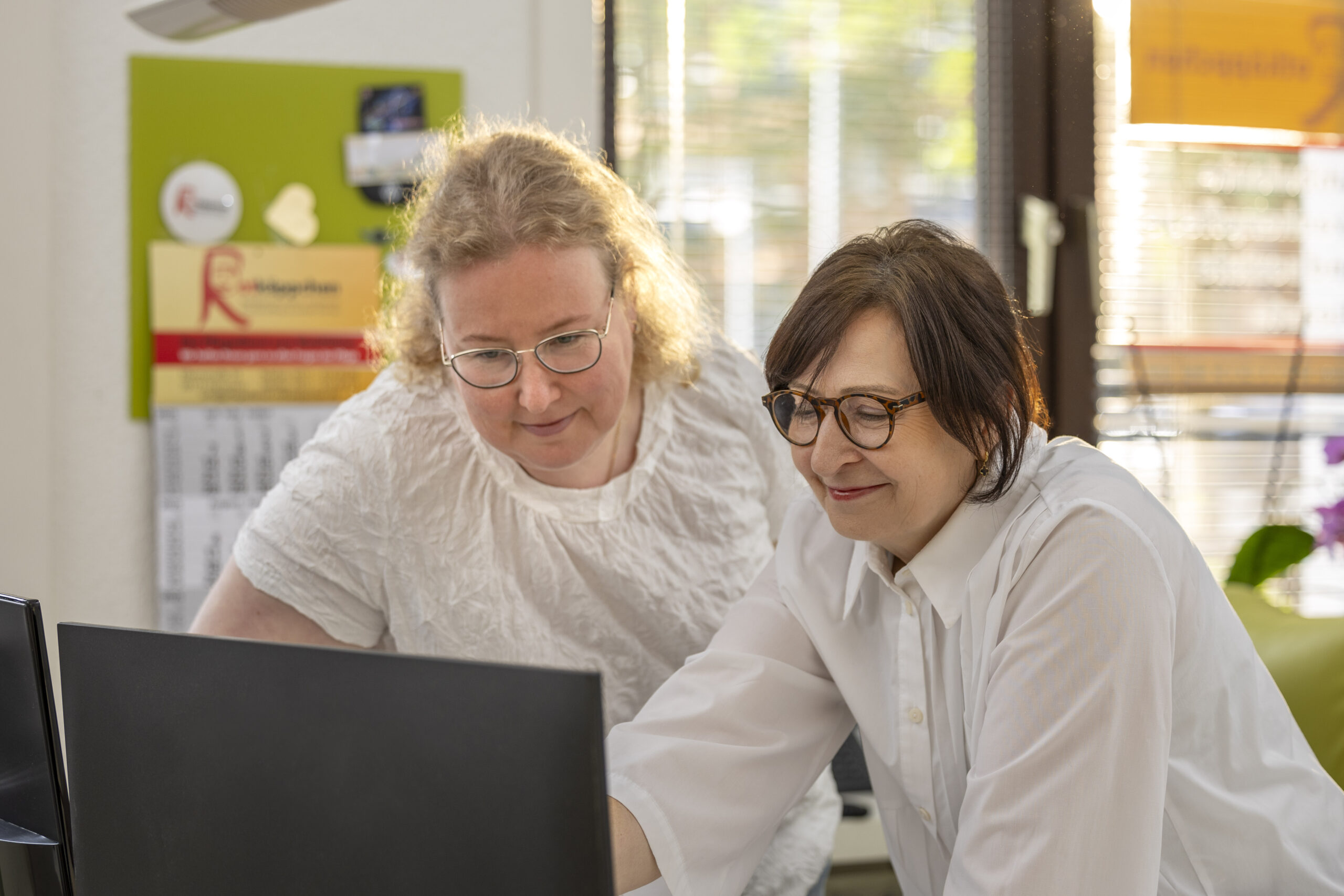 Zwei Mitarbeiterinnen koordinieren am Computer Termine und prüfen Unterlagen – Vermittlung und Beratung.