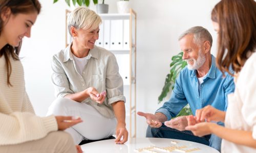 Gäste der Tagespflege sitzen am runden Tisch und spielen gemeinsam mit Steinen – freundliche Gruppenaktivität.